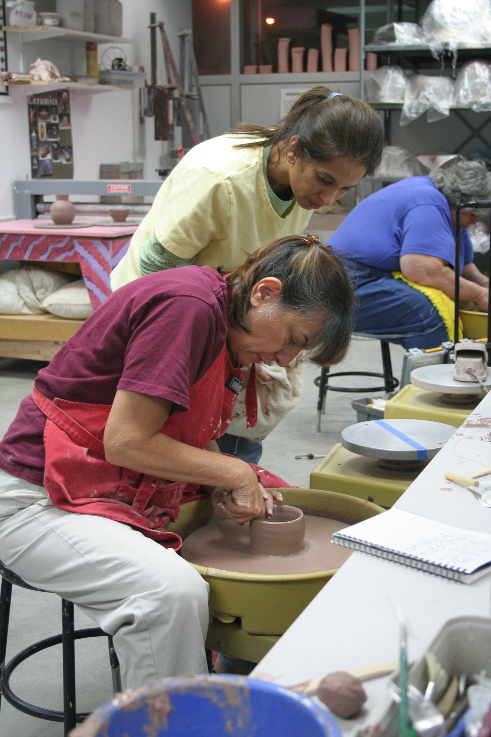 A woman artists creating a ceramic piece on the potter's wheel.