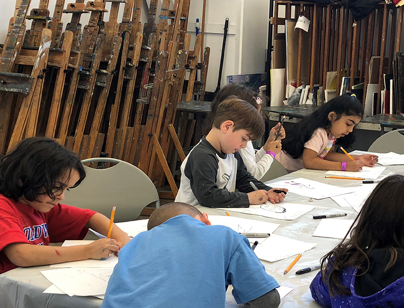 Kids creating art around a table.