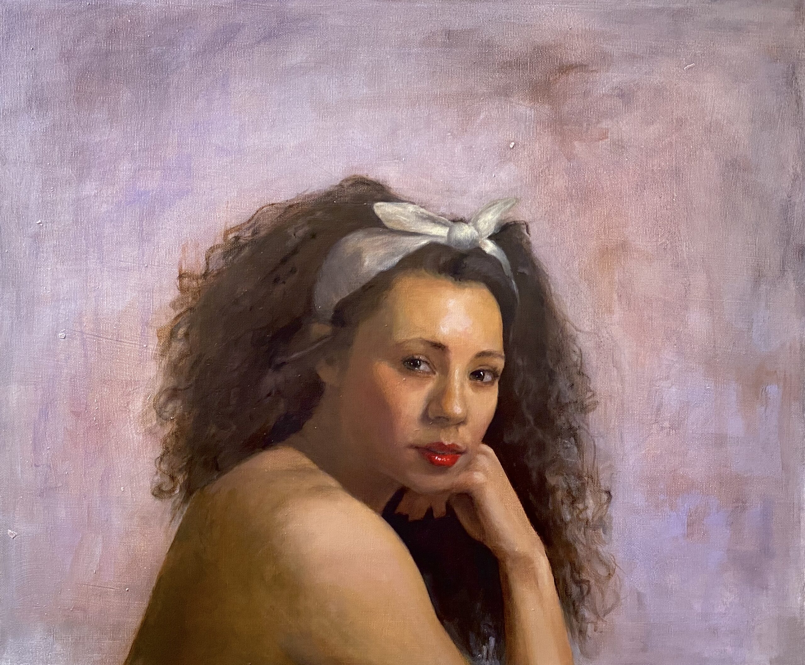 Celeste Maslovsky Flora, 2022 Oil on canvas 20 x 24 inches. It is a realistic photo of a woman with brown skin, red lips, black eyes, and curly brown hair tied up with a white ribbon.