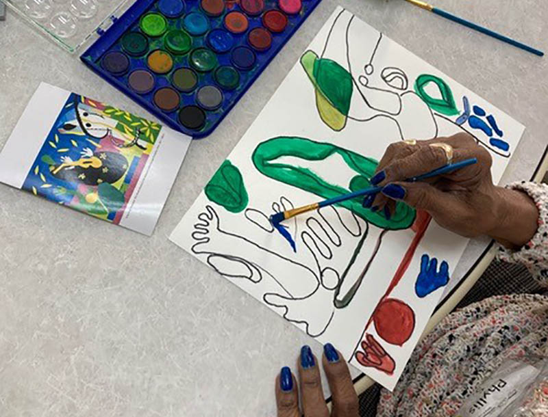 A woman painting in Art from the Heart with SAGE Eldercare.