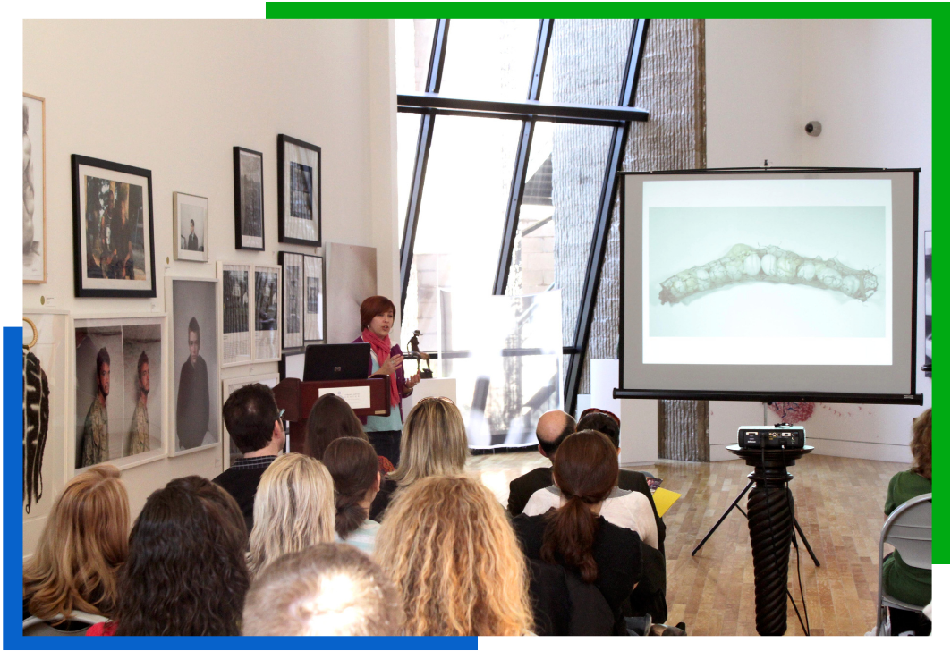 A crowd watching a woman present inside the first floor gallery.